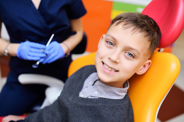 Young boy sitting in dental chair and smiling at Sierra Kids Dentistry in Reno, NV