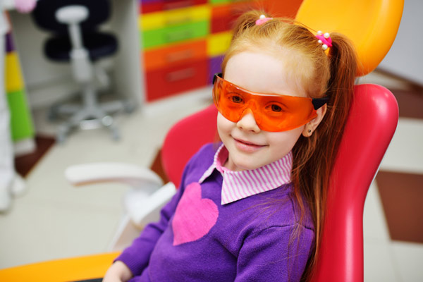 Young red headed girl with pigtails smiling in dental chair